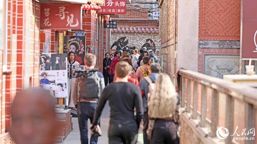 蟳埔古巷游人如织，中外游客体验簪花围，感受闽南风情。