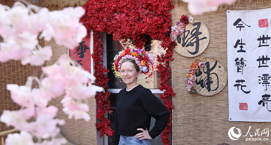 旅游达人头戴簪花围，笑立花门前